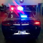 A police car with lights on parked in a garage.