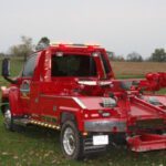 A red tow truck parked in the grass.