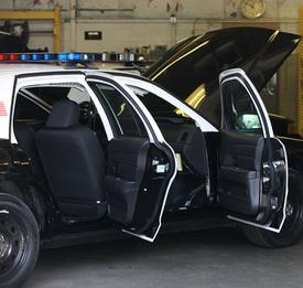 A police car with its doors open in the garage.
