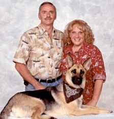 A man and woman standing next to a dog.